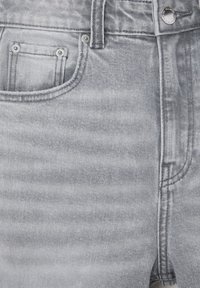 Shorts en jean gris avec une taille haute, une poche avant ornée de rivets en métal et une texture subtile. Aspect délavé sur l'ensemble.