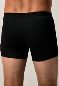 Boxer neri con una texture morbida e una cintura elastica con il logo "JP1880". Design aderente che si estende fino a metà coscia.