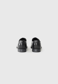 Black leather dress shoes with a rounded toe, smooth surface, and a low heel. Features subtle stitching details on the back.