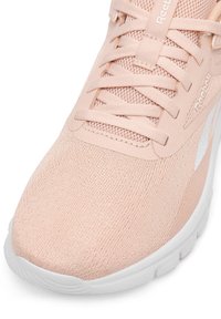 Detailný záber na svetloružový Reebok sneaker s sieťovaným zvrškom, zodpovedajúcimi šnúrkami a bielou textúrovanou podrážkou.