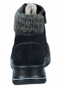 Bottine en daim noire avec un revers en tricot gris, fermeture éclair et semelle texturée. Présente des coutures visibles et un logo sur le côté.