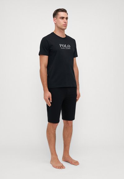 Tricou din bumbac negru cu logo-ul "POLO RALPH LAUREN", asociat cu pantaloni scurți negri. Design simplu, ajustat, cu mâneci scurte și fără modele.