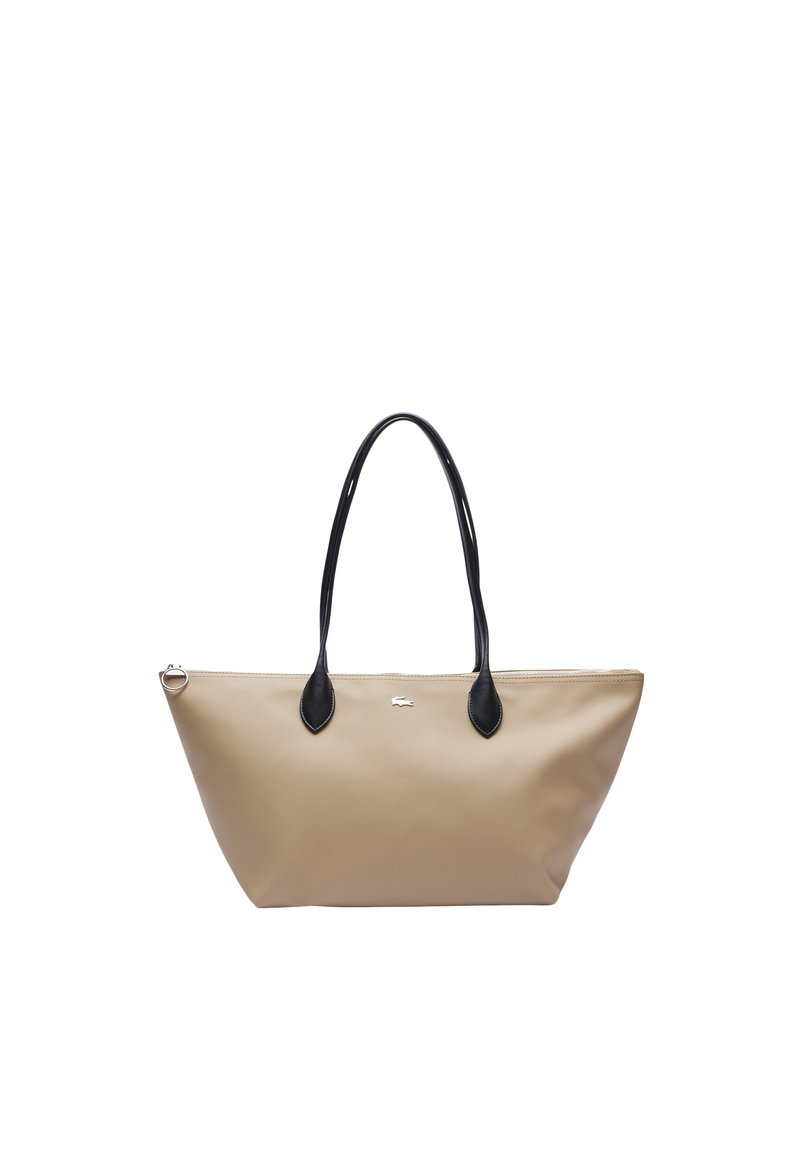 Torba typu tote w beżowym materiale syntetycznym z czarnymi skórzanymi akcentami. Posiada dwa długie uchwyty oraz logo na środku. W kształcie trójkąta.