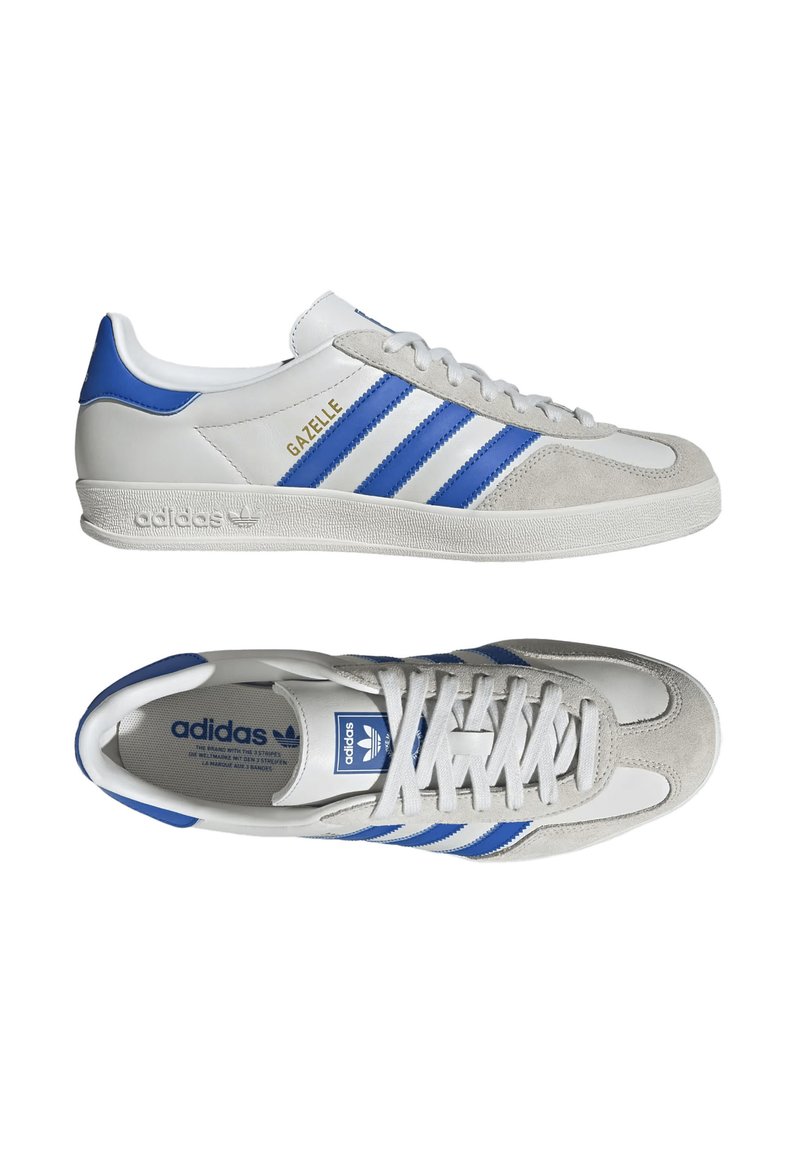 Baskets Adidas Gazelle classiques en blanc avec des accents bleus et gris, comportant trois rayures bleues et une semelle texturée.