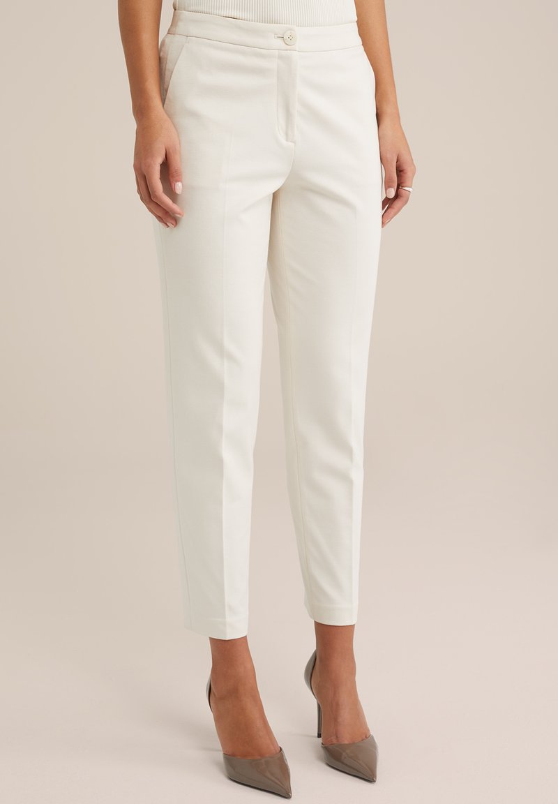 Pantaloni bianchi su misura con una vestibilità slim, dotati di chiusura a bottone, tasche laterali e una texture di tessuto liscia. Tagliati alla caviglia.
