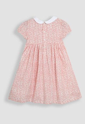 Robe florale rose avec des manches courtes bouffantes, col en Peter Pan blanc et fermeture à boutons dans le dos. Tissu texturé et évasé.