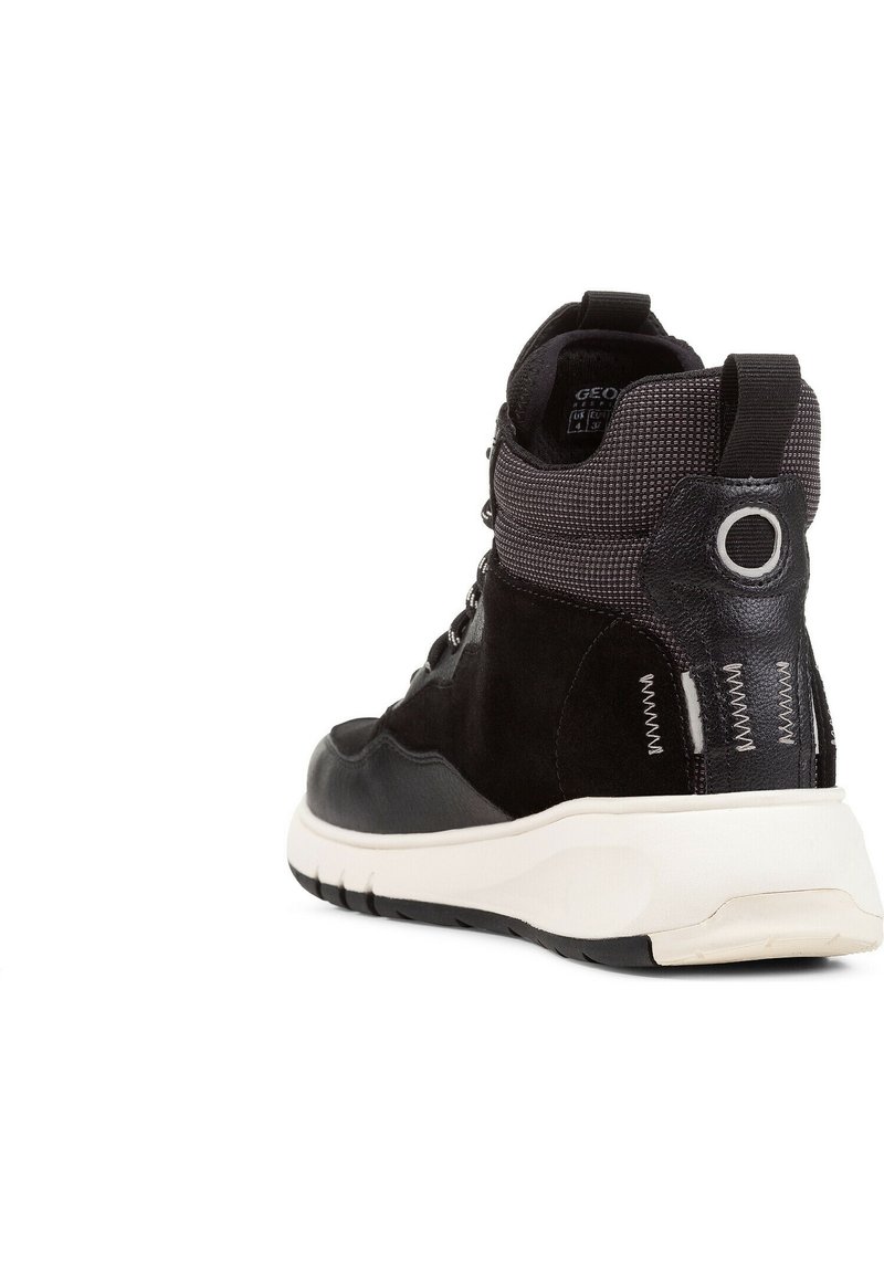 Baskets montantes noires avec une tige en suède et synthétique, un col en textile à motif, et une semelle en caoutchouc blanche. Comprend des coutures accentuées et un détail de logo.