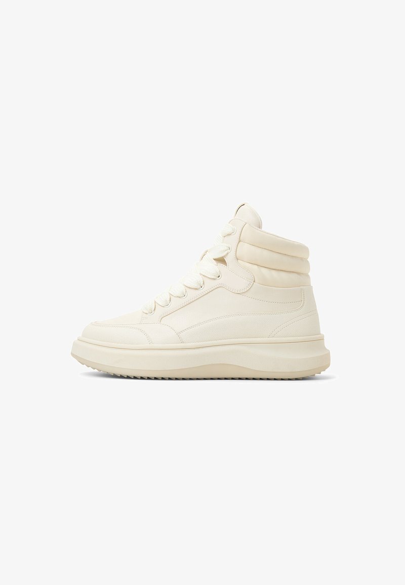 Zapatillas altas de cuero blanco roto con soporte acolchado para el tobillo, cordones planos y una suela de goma texturizada para agarre. Diseño limpio y minimalista.