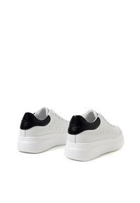 Bílé tenisky s hladkým koženým povrchuem, s černým koženým akcentem na patě a bílou gumovou podrážkou. Jemné perforace pro prodyšnost.