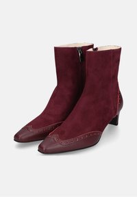Bordeaux kleurige enkellaarzen van suede met een puntige neus, voorzien van contrasterende leren accenten en decoratieve stiksels. Zijkant ritsluiting.