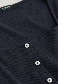 Marineblaues, geripptes Oberteil mit quadratischem Ausschnitt, fünf weißen Knöpfen in der Mitte und glatter Textur. Markenlabel: NEXT.