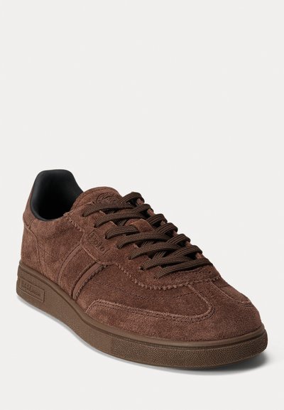Baskets en suède marron avec lacets plats, semelle en caoutchouc et détails texturés. Présente un design minimaliste et des accents de couture contrastée.