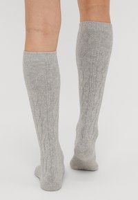 Sivé ponožky po kolená s textúrovaným pleteným vzorom, s rebrovanými manžetami a mäkkou, elastickou tkaninou pre pohodlné nosenie.