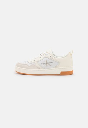 Niskie białe i beżowe buty sportowe Calvin Klein z przodem na sznurowadła, akcentami z zamszu, oznaczoną boczną panelem i gumową podeszwą.