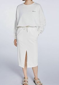 Sweat-shirt blanc et jupe midi assortie avec une fente frontale, en tissu doux. Comprend une taille à cordon et des poches latérales.