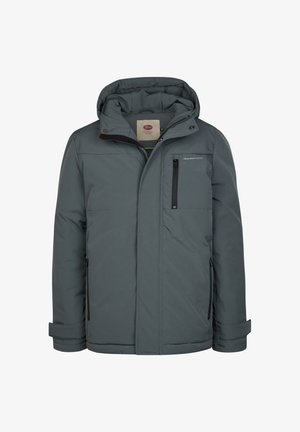 Rødhåret dreng iført en grå hættetrøje, mørkegrøn sweatshirt, blå jeans og lysebrune snørestøvler, står mod en hvid baggrund.