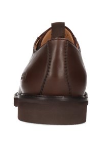 Zapatos de cuero marrón con un acabado liso, vista trasera que muestra una forma redondeada, detalle de costuras y una lengüeta de tela en el talón.