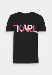 Camiseta de algodón negra con un gráfico en negrita y multicolor "KARL" en tonos rosa y púrpura, con el texto "LAGERFELD" a un lado.