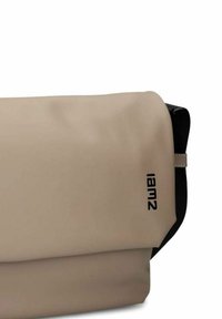 Borsa a tracolla di tessuto color sabbia con interno nero e logo "lamiz" sul bordo del flap, design semplice e fluido.