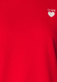 Czerwona bawełniana koszulka T-shirt z białym haftem z napisem "LOVE" oraz wzorem serca. Tkanina ma gładką fakturę i klasyczny krój.