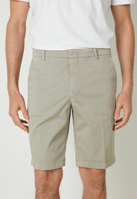Ljusgrå shorts i ett slätt tyg, med sidofickor, slät front och uppkavlade avslut för en ren finish.