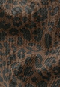 Tissu marron avec un motif léopard noir irrégulier et une texture de tissage diagonal visible.