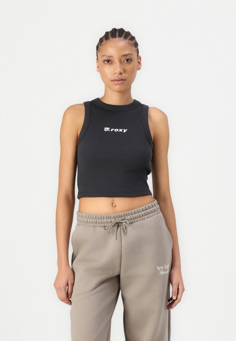 Black ribbed crop top with a round neckline and white "Roxy" logo; paired with light gray sweatpants featuring an elastic waist and logo.