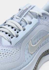 Világoskék Nike Pegasus sportcipők hálós és texturált anyagokkal rendelkeznek, szürke fűzőkkel, ezüst pipa logóval és jellegzetes panel díszítésekkel.