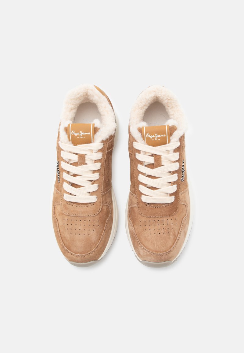 Sneaker scamosciato color tan con fodera beige soffice, lacci beige e dettagli perforati sulla punta. Suola bianca e etichetta del marchio sul lato.