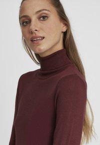 Pull marin bordeaux en maille texturée. Il présente une silhouette ajustée et des détails côtelés au niveau du cou.