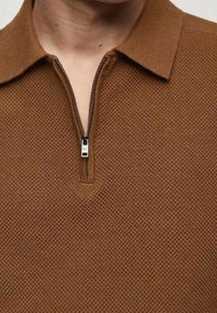 Brown knitted polo shirt with a zippered collar. Features a textured pattern and a silver zipper with a rectangular pull tab.