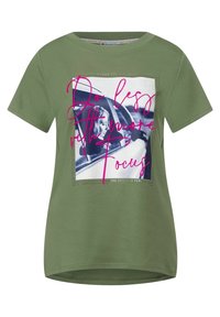 Olivgrön t-shirt, rund halsringning, korta ärmar. Har ett grafiskt tryck med rosa text och en svartvit bild inom en rektangulär kant.