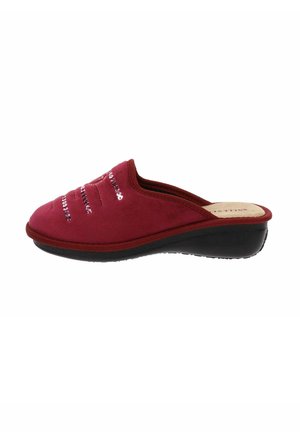 Scarpa slip-on in suede rosso con suola nera bassa, caratterizzata da cuciture orizzontali e dettagli metallici sulla parte superiore, che offrono una texture morbida.