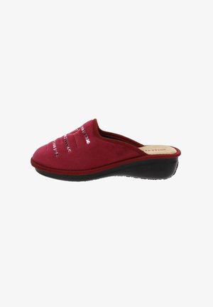 Chaussure slip-on en suede rouge avec une semelle noire basse, présentant des coutures horizontales et des accents métalliques sur le dessus, offrant une texture douce.