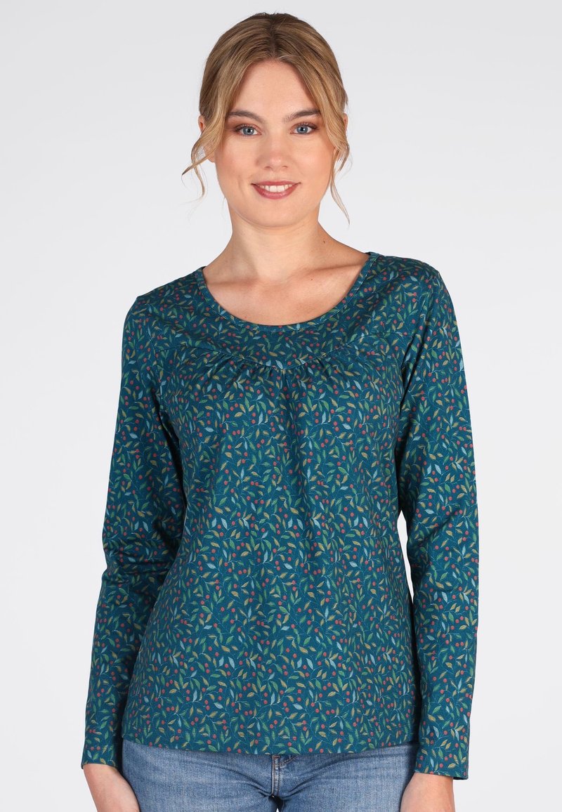 Teal Langarmshirt mit Rundhalsausschnitt und Raffung, das ein mehrfarbiges Blattform-Muster aufweist. Kombiniert mit blauen Jeans.