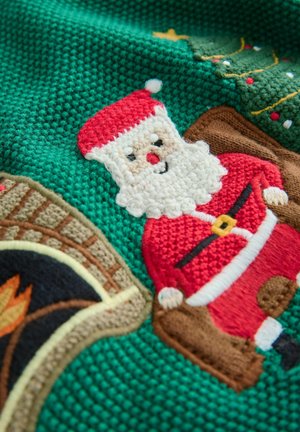 Pletená zelená látka s barevným výšivkou Santa Klause, hnědým krbem a zdobeným vánočním stromkem.