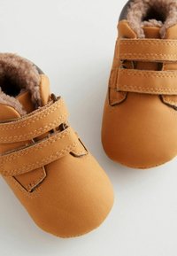Braune Baby-Schuhe aus kunstleder mit zwei Klettverschlüssen, runden Zehen und weichem Fleece-Futter, verziert mit Stickdetails entlang der Kanten.