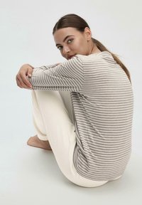 Long-sleeve top in light gray with white stripes, paired with cream-colored pants. Soft fabric, relaxed fit, featuring a rounded neckline.