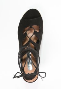 Infradito in suede nero con tacco a cuneo, design con cinturini incrociati, suola piatta e dettagli con lacci, caratterizzati da una fodera interna liscia.