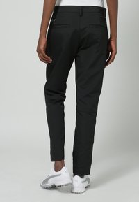 Svarta, slim-fit byxor gjorda av ett slätt tyg. Har två bakfickor, minimalistisk design och en liten logotyp på midjebandet.