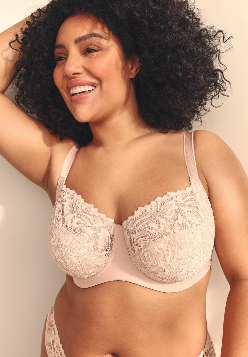 Lace bralette in lichtbeige met gegolfde randen, voorzien van een bloemenpatroon en verstelbare bandjes. Glad band onder de cups.