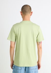 T-shirt vert clair à manches courtes avec un col rond, fabriqué en coton doux. Il présente un design uni et une coupe décontractée.