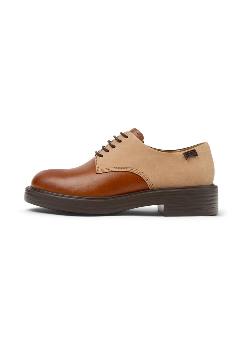 Scarpe in pelle marrone e beige con punta arrotondata, finitura liscia, design con lacci e suola marrone testurizzata. Presenta un'etichetta del marchio sul lato.