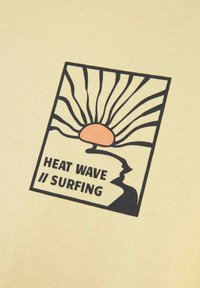 Camiseta amarilla con un diseño gráfico que presenta un sol y líneas onduladas, texto que dice "OLA DE CALOR // SURFING", detalles en negro y naranja.