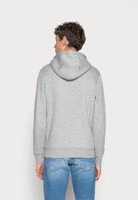Gray sweatshirt featuring a hood and ribbed cuffs, paired with light blue jeans. The fabric appears soft with a relaxed fit.