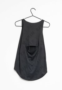 Zwarte mouwloze sporttanktop met een open rugontwerp, hangend aan een zwarte draadhanger tegen een witte achtergrond.