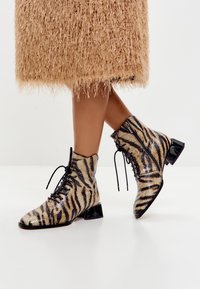 Tijger gestreepte enkelboots met een glanzende afwerking, voorzien van zwarte veters en een zijrits, aangevuld met een blokhak.