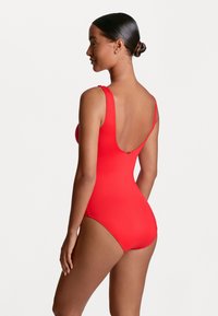 Maillot de bain une pièce rouge avec un design à dos décolleté, des bretelles larges et un textile doux. Présente des coutures minimales et une coupe ajustée.