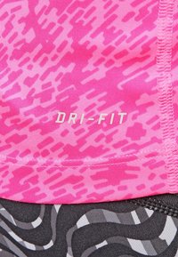 Tela Dri-Fit rosa con un patrón texturizado, que presenta un atrevido logo blanco "DRI-FIT" y un diseño negro ondulado en el dobladillo inferior.