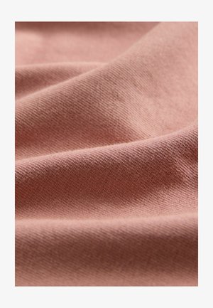 Ljust rosa stickat tyg som visar fin textur och mjuka veck. Materialet verkar slätt med en lätt glans, vilket framhäver dess töjbarhet.